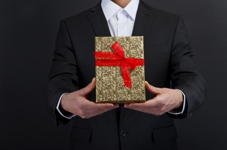 close up of man hands holding gift box over dark backgroundの写真素材