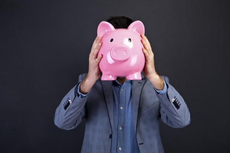 portrait of young man holding a piggy bank against a grunge backgroundの写真素材