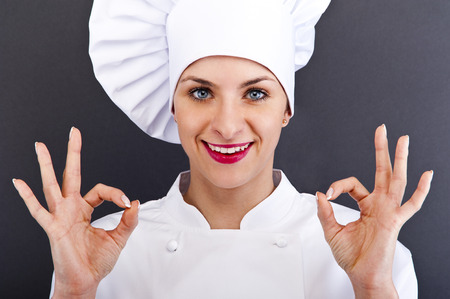 Attractive cook woman showing ok over dark backgroundの写真素材