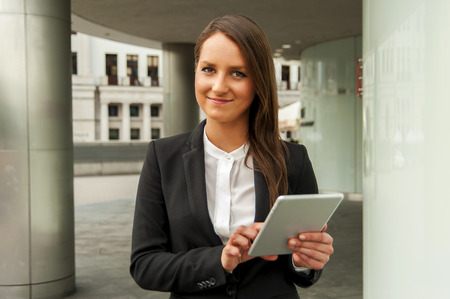 Young businesswoman touching tablet in the city. Smiling.の写真素材