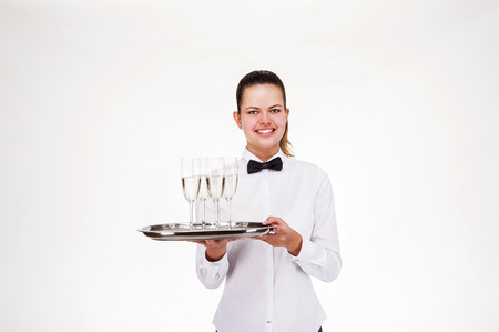 Woman in waiter uniform holding tray and glasses with champagne, smiling.の写真素材