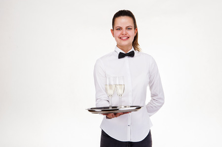 Woman in waiter uniform holding tray and glasses with champagne, smiling.の写真素材