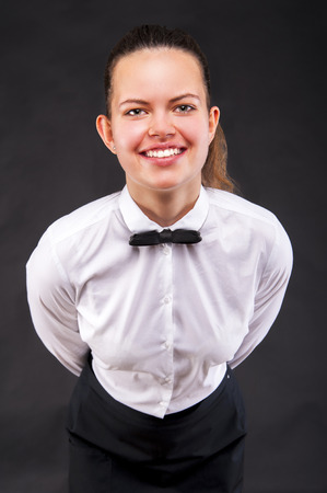Young woman in waiter uniform over dark background.の写真素材