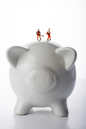 Miniature people workers over pigy bank on white backgroundの写真素材