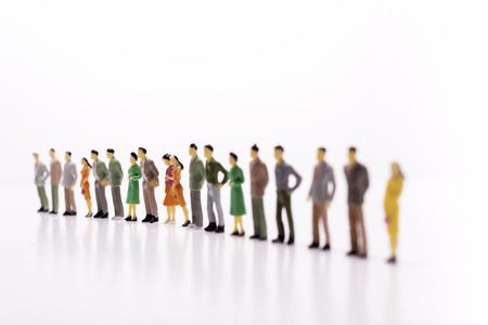 Miniature people standing in line over white background.の写真素材