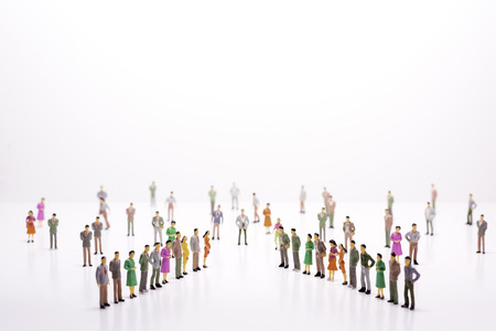 Miniature people in two lines across to each other over white background.の写真素材