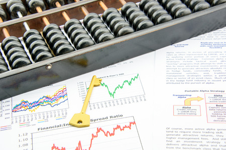 Chinese abacus with a golden key on on business and financial summary reports. A long-term key success investment concept.の写真素材
