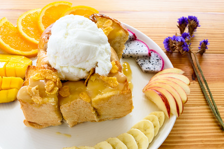 Honey toast with coconut ice cream and fruits including orange, mango, banana, apple and dragon...