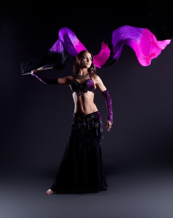 young beautiful girl in arabic costume dance with fantail and purple veil in darkの写真素材
