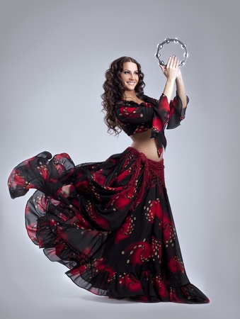 Young beauty woman dance in gypsy costume with tambourine isolatedの写真素材