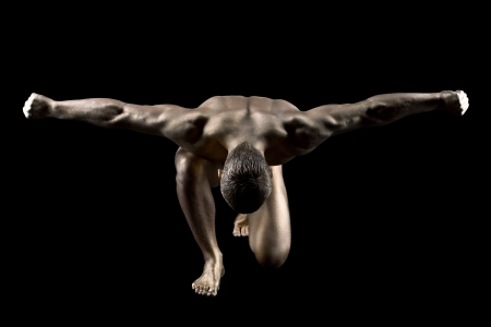 Strong nude man with gold skin make up posing in darkの写真素材