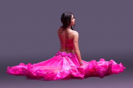Studio portrait of dancer in pink costume sitting on floorの写真素材