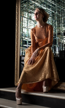 Charming blonde posing in fashionable golden dressの写真素材