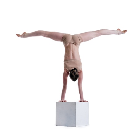 Flexible woman posing doing exercises on cube in studio
