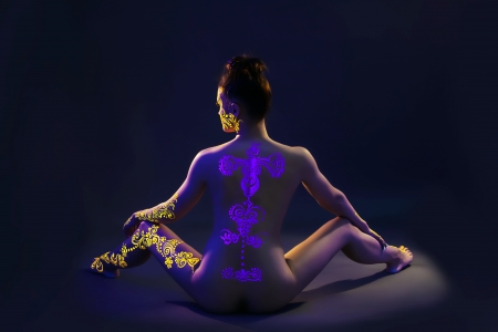 UV glowing pattern on back of nude slim model, close-upの写真素材