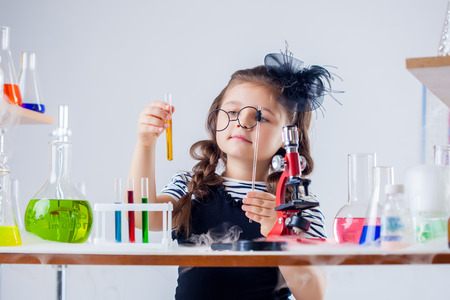 Funny girl looking through her glasses at test tube in labの写真素材