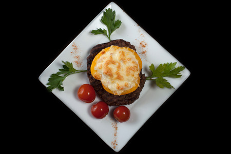 Tasty beef steak with cheese and vegetables, isolated on blackの写真素材