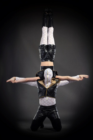 Shot of acrobatic stunt performed by go-go dancers, on gray backgroundの写真素材