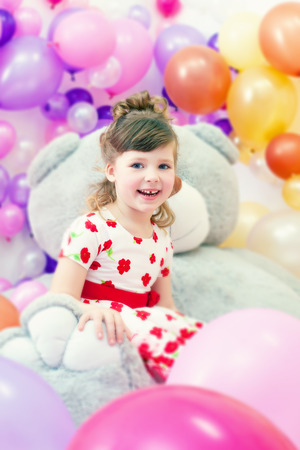Image of merry little girl posing in playroom with big teddy bearの写真素材