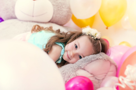 Portrait of adorable little girl lying on plush bearの写真素材