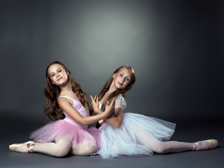 Studio shot of two graceful ballet dancers, on gray backgroundの写真素材
