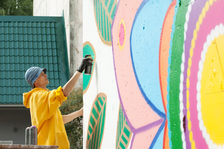 Image of creative young man drawing with spray can on wallの写真素材