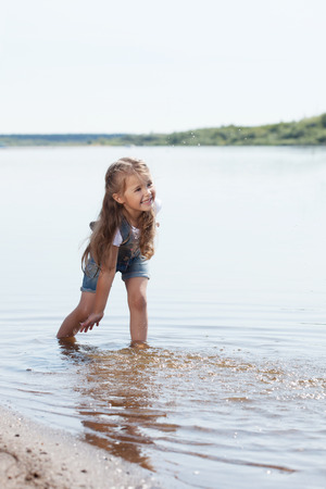Image of cheerful little girl playing in lakeの写真素材