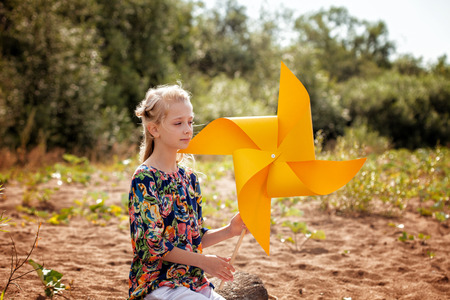 Thoughtful girl posing with paper windmill, close-upの写真素材