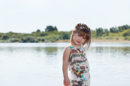 Smiling little girl posing by river, close-upの写真素材