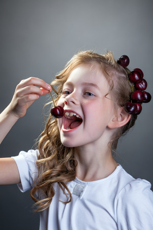 Image of cheerful little girl wants to taste cherryの写真素材