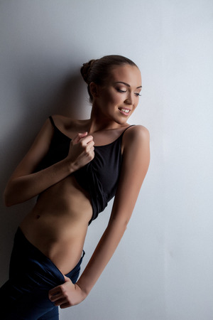 Studio shot of sexy tanned model bared her waist, on gray backgroundの写真素材