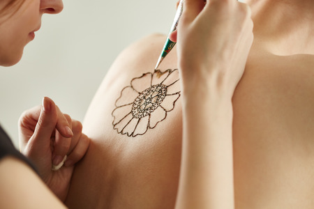 Mehndi master drawing with henna on models back, close-upの写真素材