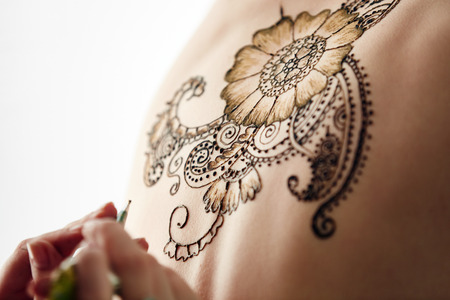Mehndi. Beautiful henna patterns in process of applying on models backの写真素材