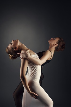 Sexy girls dancing in pair of erotic dance. Studio photo, on grey backgroundの写真素材