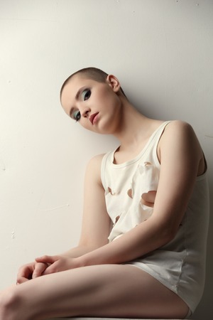 Studio shot of pretty skinhead girl in ragged t-shirtの写真素材