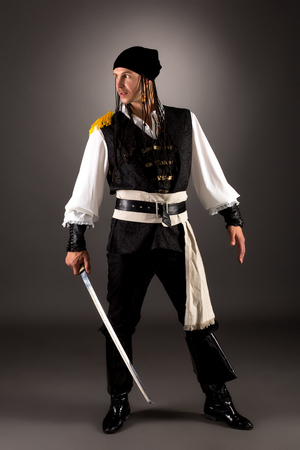 Daring pirate with saber. Studio photo on gray backgroundの写真素材