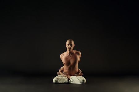Middle-aged yogi posing in lotus position, on gray backgroundの写真素材