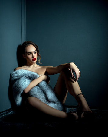 Studio photo of naked model posing with expensive fur coatの写真素材