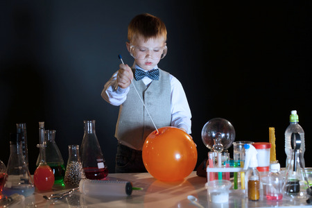 Image of concentrated pupil pierces balloon in lab, close-upの写真素材