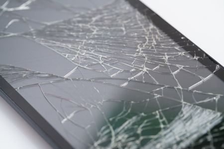 Closeup of mobile smartphone with broken screen isolated on white background, selective focusの写真素材