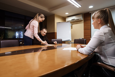 Businesspeople taking deal.  Businessman signing contract after making agreement while his female...