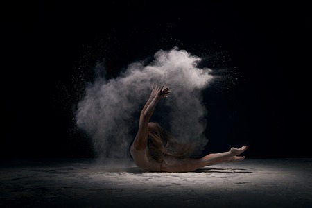 Gymnast in ecru bodysuit in cloud of white dustの写真素材