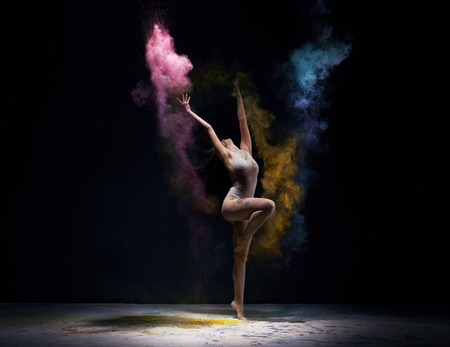 Gymnast in ecru bodysuit with colored dust aroundの写真素材