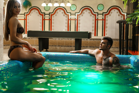 Young sexy pair bathing in luxurious swimming pool