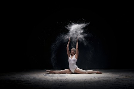 Graceful girl doing split in white powder cloudの写真素材