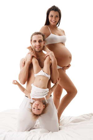 Pregnant young woman posing with her husband and childの写真素材