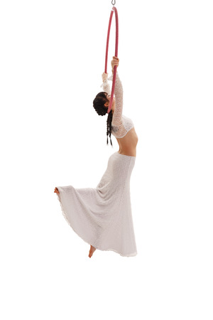 Young girl in white dress hangs on hoop in studioの写真素材