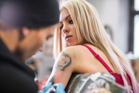 Sexy blonde and tattoo master at work in studioの写真素材
