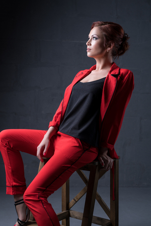Woman in fashionable red pantsuit in studioの写真素材