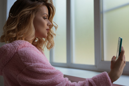Gorgeous sexy blonde making selfie near windowの写真素材